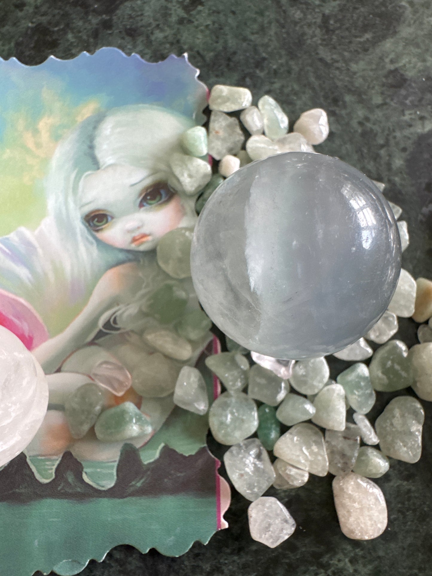 Illustration of an anime-like girl with a crystal ball and stones.