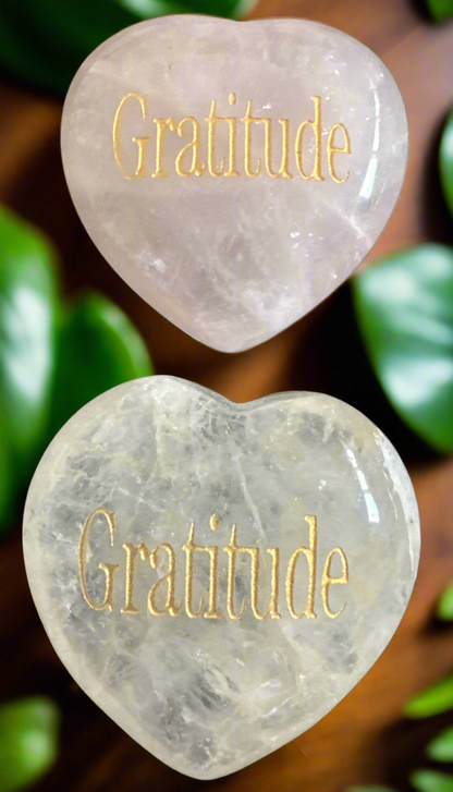 Two heart-shaped clear stones with the word "Gratitude" engraved in gold.