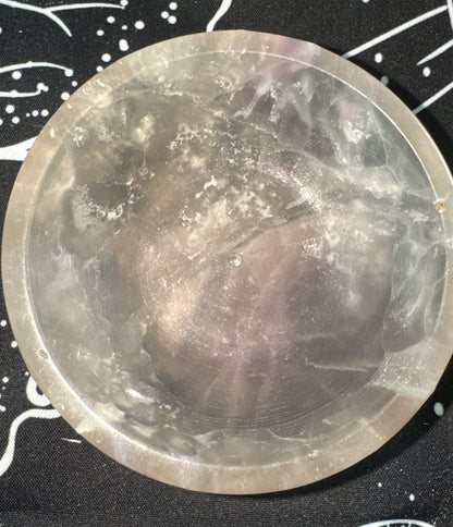 Translucent, gray crystal bowl on a black and white patterned cloth.
