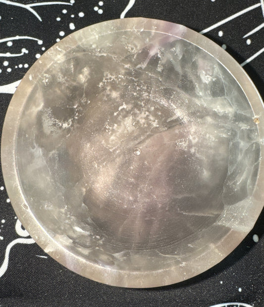 Translucent, gray crystal bowl on a black and white patterned cloth.
