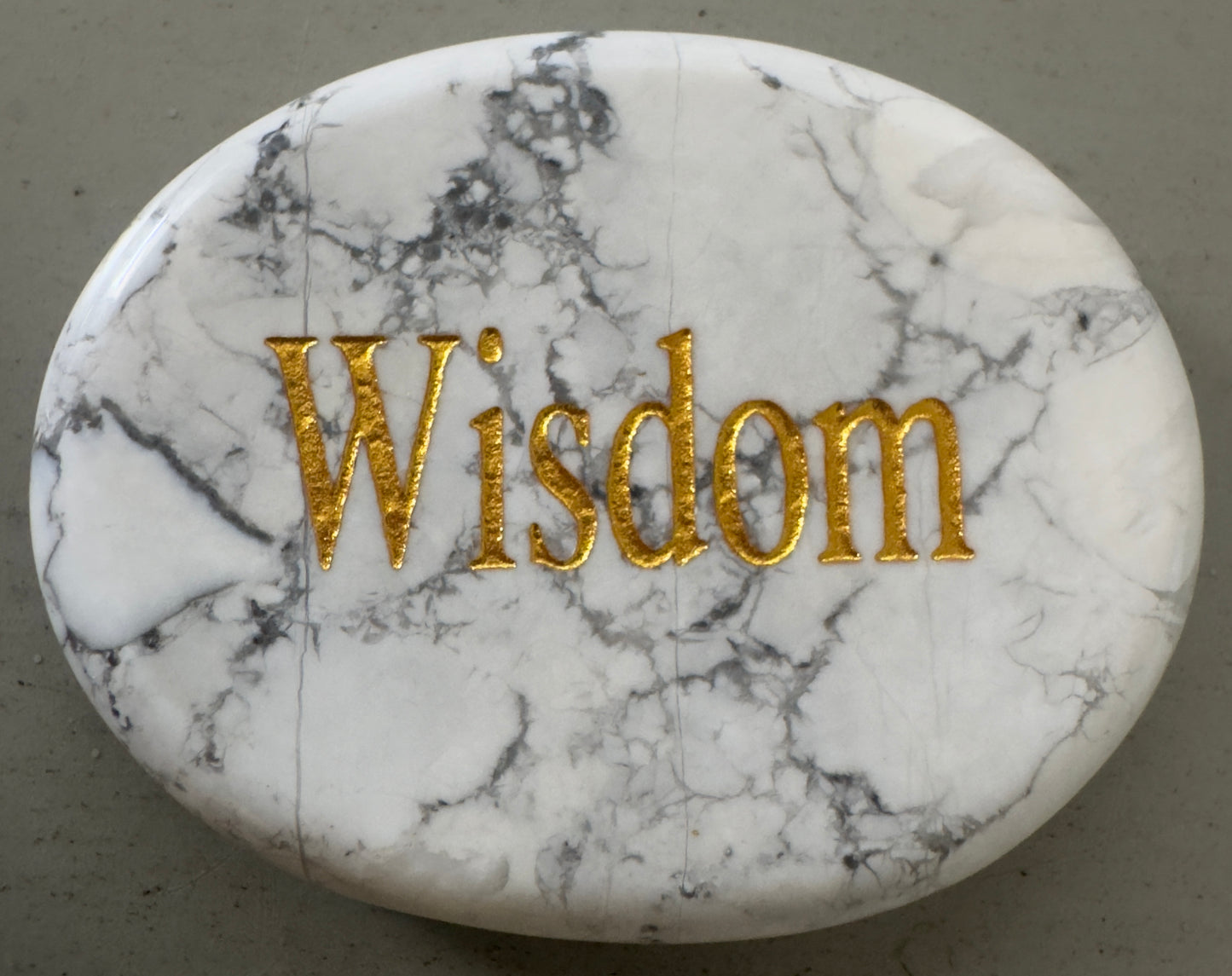 Oval, white marble stone with gold lettering: "Wisdom".
