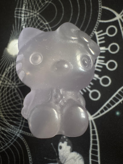 Translucent purple Hello Kitty resin figure on patterned black surface.