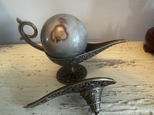 Ornate metal genie lamp with marble sphere.
