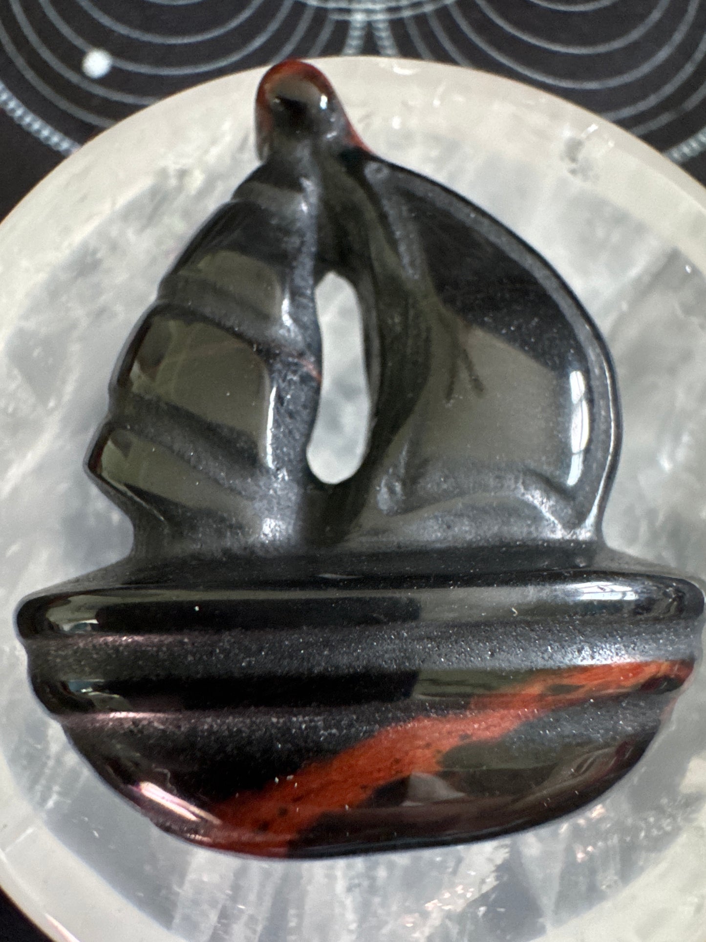 Carved obsidian boat with red stripe.