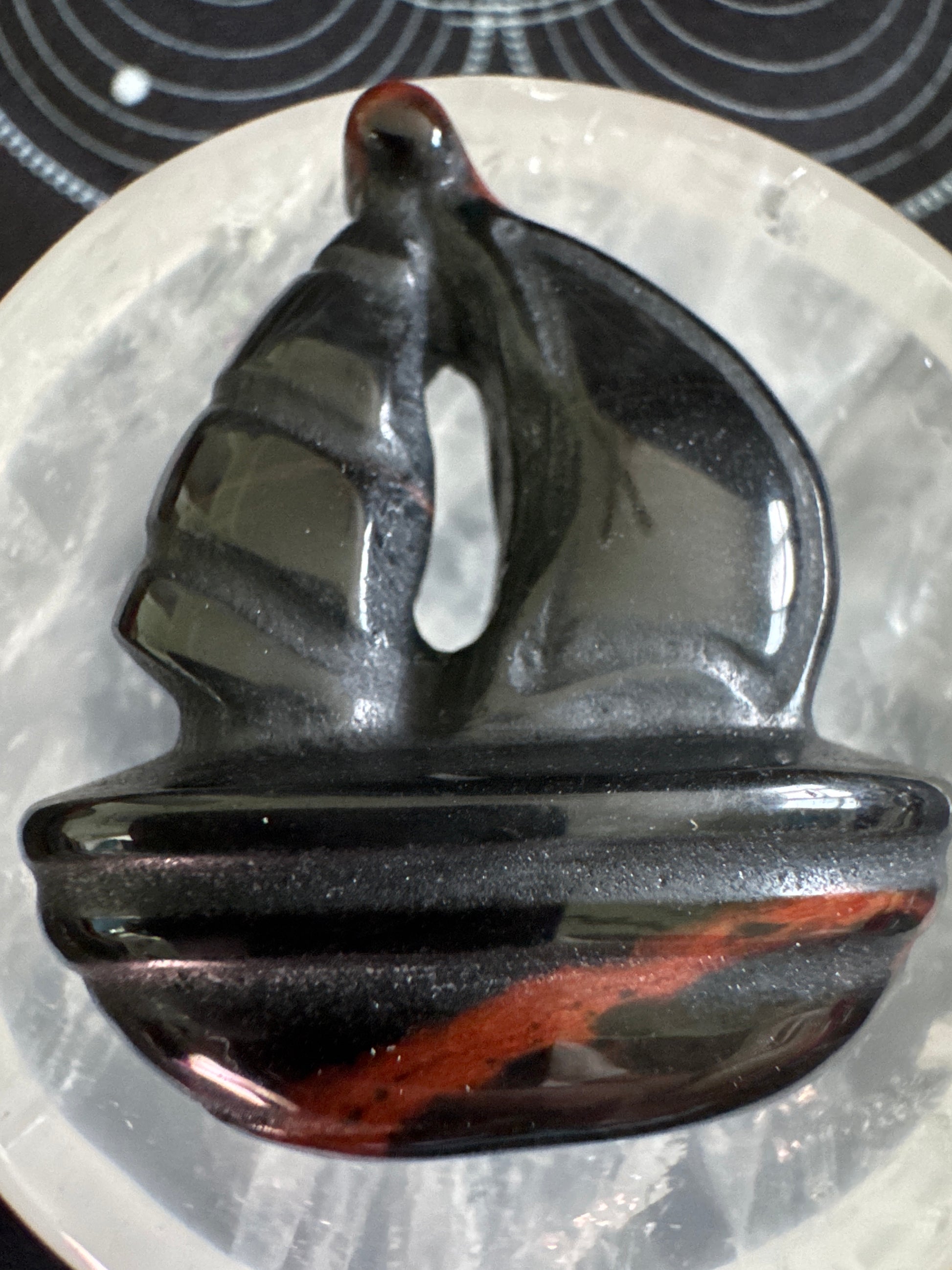 Carved obsidian boat with red stripe.