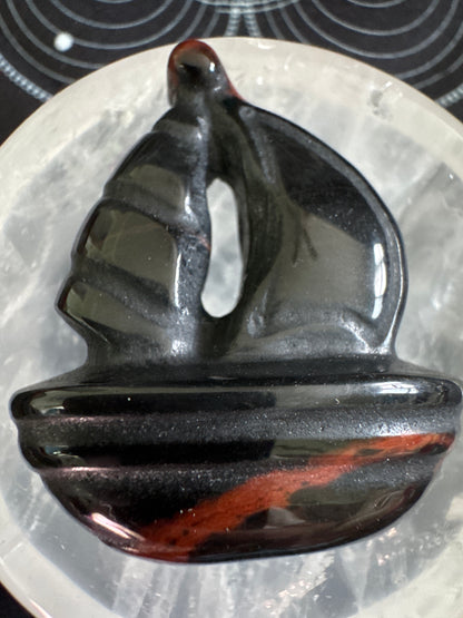 Carved obsidian boat with red stripe.