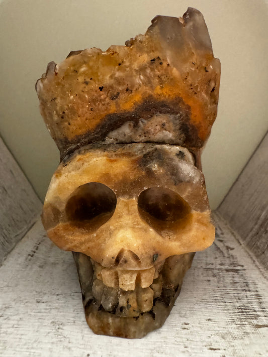 Carved quartz skull with large open sockets and brown striations.