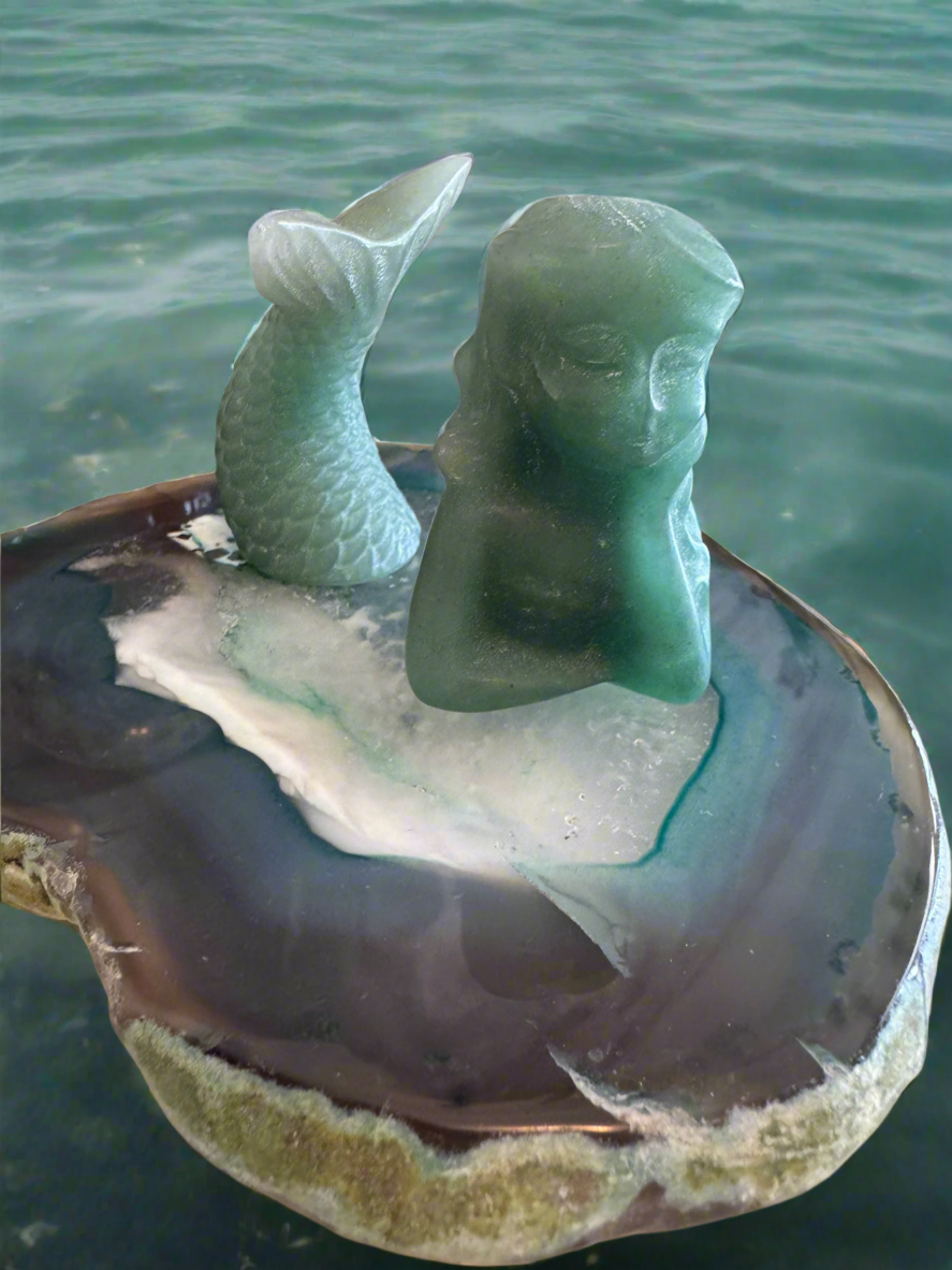 Two piece aventurine carving resting on an agate slab 
