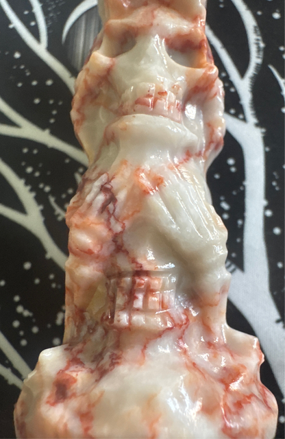 Close-up of a white and red marble skull statue.