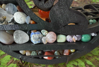 Close-up of a black wooden shelf filled with various colorful stones and crystals.