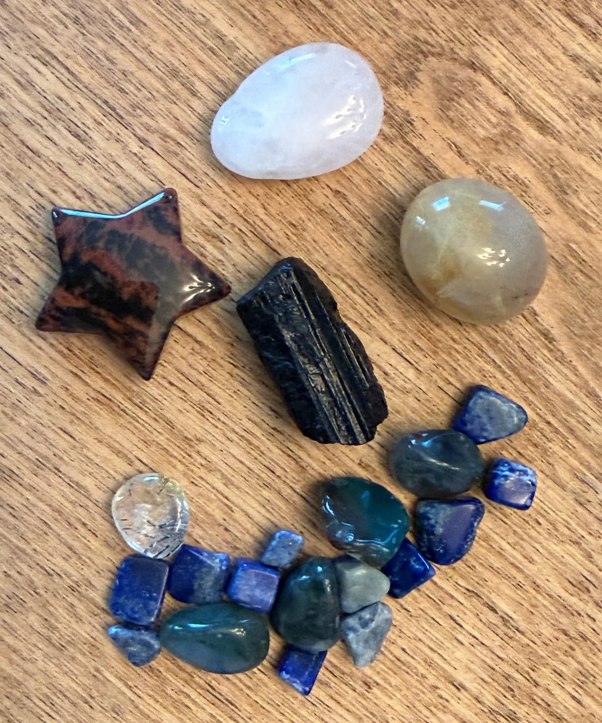 photo of components - black tourmaline, calcite tumbles, sodalite gravel, black tourmaline rough piece, clear quartz egg