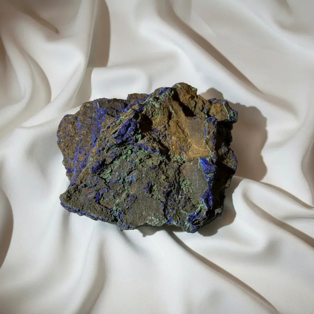 Azurite mineral specimen with a brown and gray matrix, featuring prominent purple veins and patches of golden-yellow mineralization