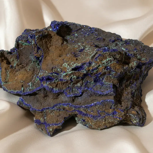Azurite mineral specimen with a brown and gray matrix, featuring bright blue veins and patches of metallic iridescent material.