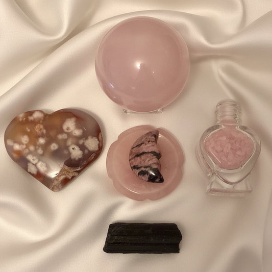Rose Quartz sphere, worry stone, rhodonite carved crescent moon, glass wish bottle filled with rose quartz chips, flower agate carved heart and black tourmaline specimen 