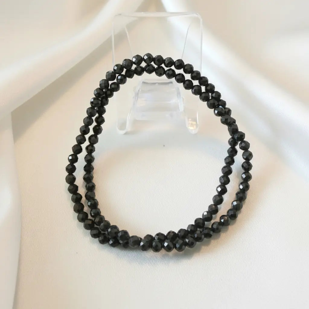 close up of two 3.5mm multi facet black obsidian elastic bracelets