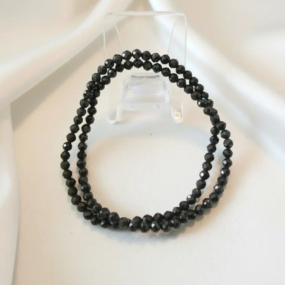 close up of two 3.5mm multi facet black obsidian elastic bracelets