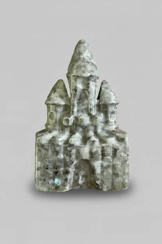 close up labradorite carved castle showing light and dark greens mixed with white inclusions 