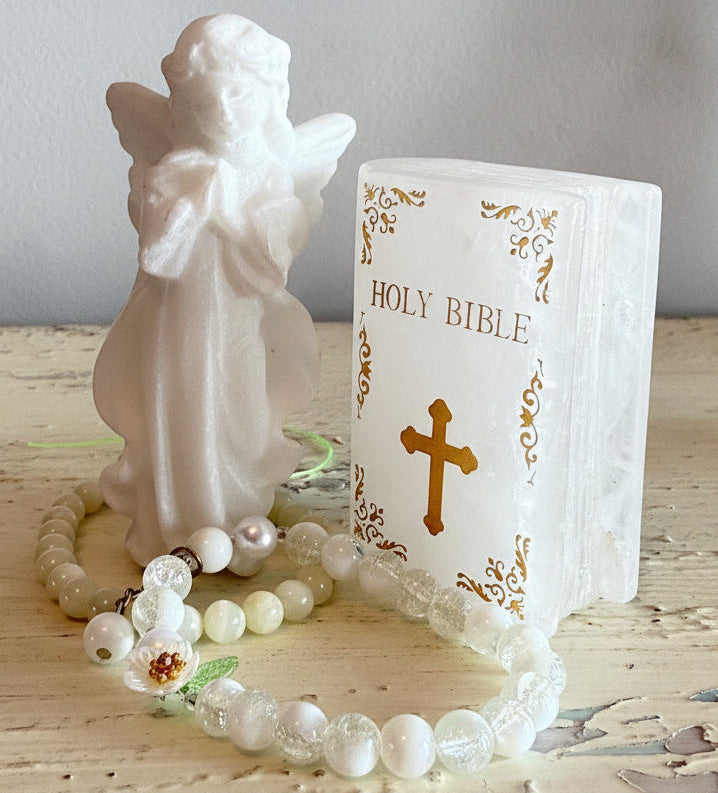 White Calcite carved angel set. Calcite Carved and gold tone letters, cross and edge decoration. Two bead bracelets on the table with carvings 