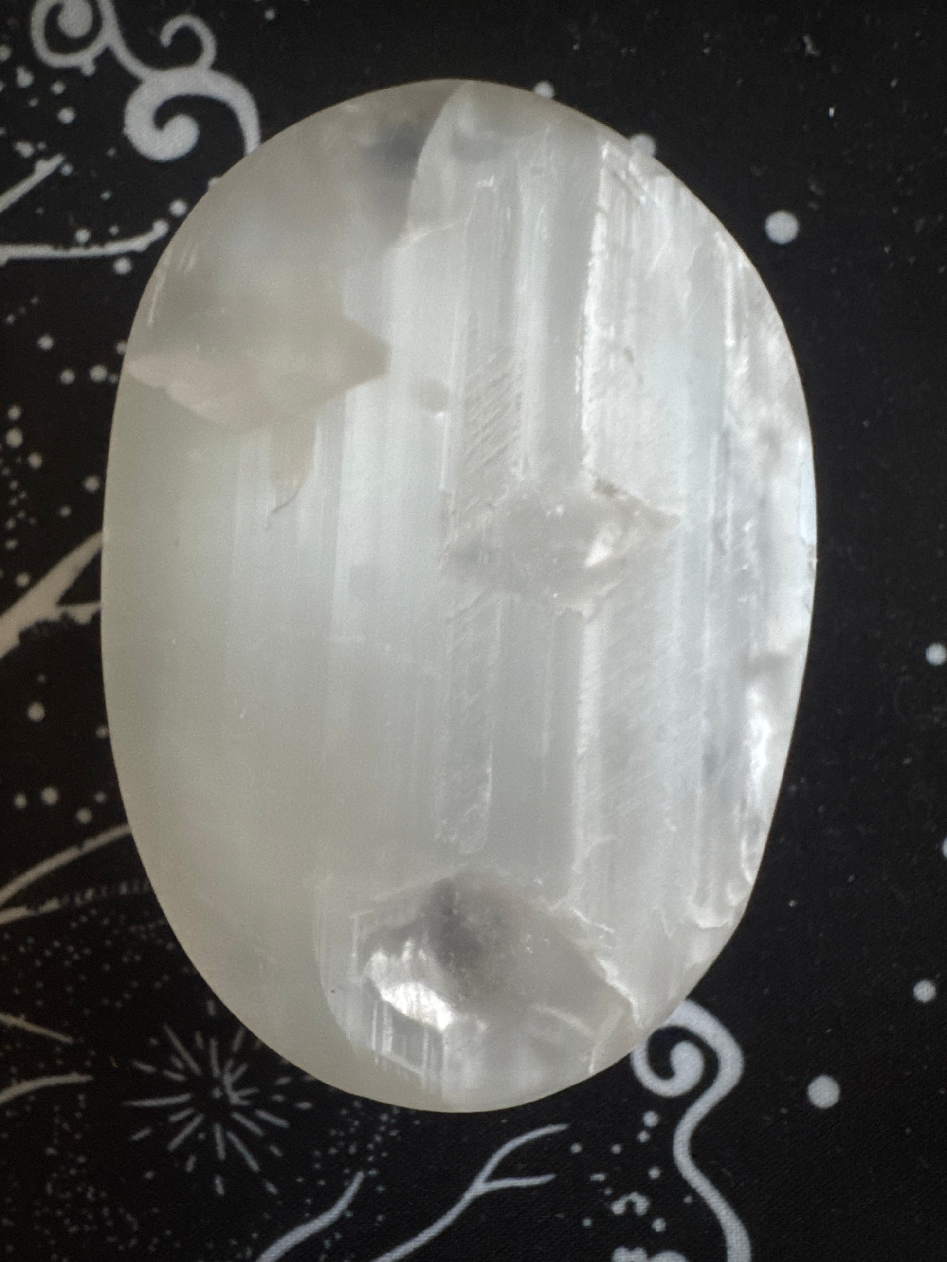 Translucent selenite crystal on a patterned black cloth.