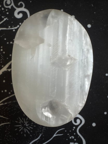 Translucent selenite crystal on a patterned black cloth.