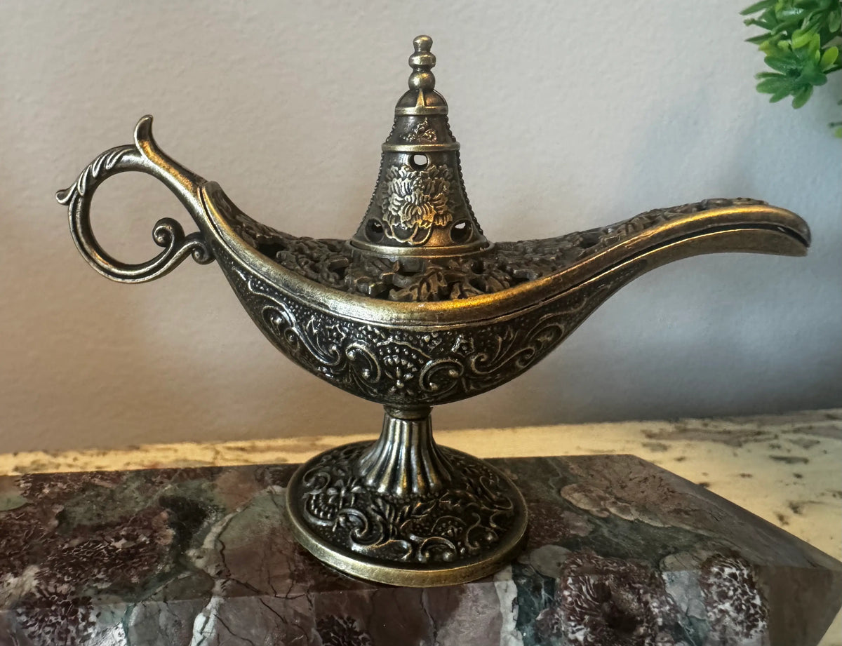 Ornate brass genie lamp on marble.
