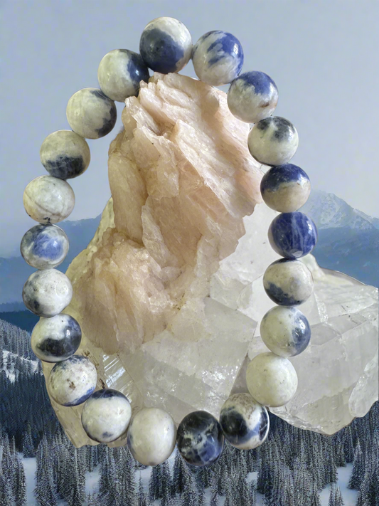 Close-up of a sodalite beaded bracelet draped over a quartz crystal.