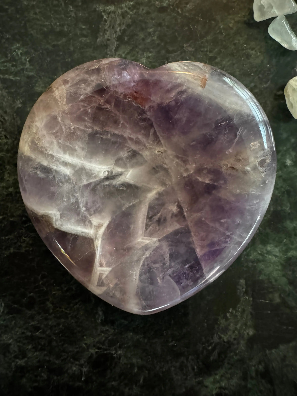 Amethyst worry stone shaped like a heart purples on a green background