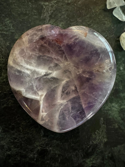 Amethyst worry stone shaped like a heart purples on a green background