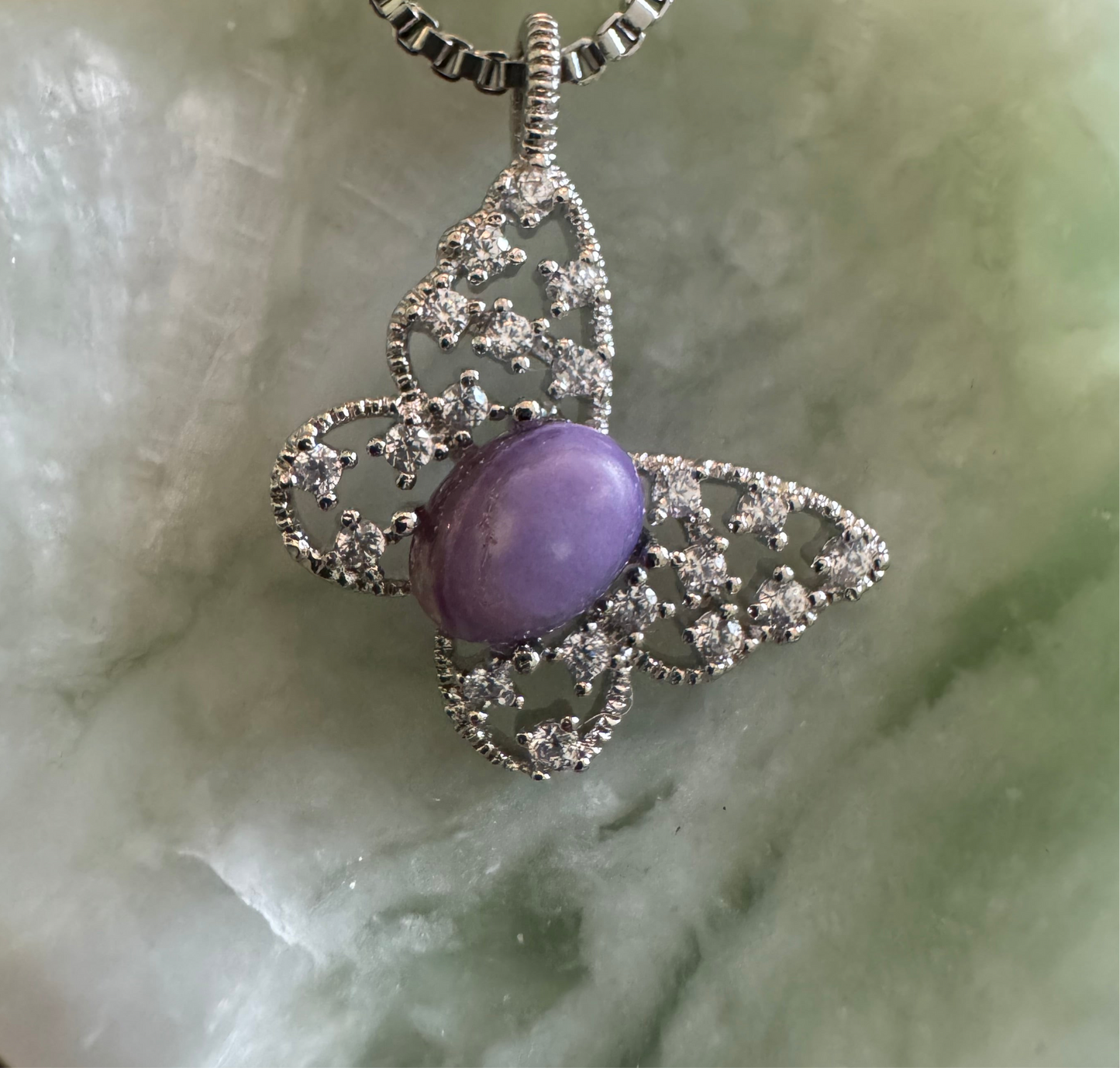Butterfly pendant with purple stone and silver accents.
