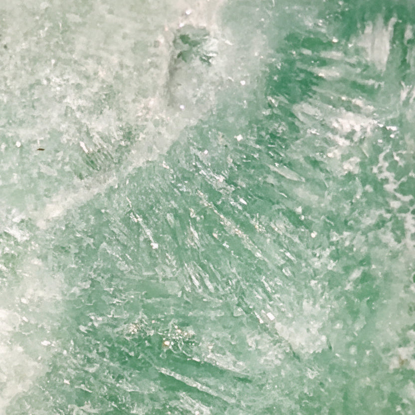 close up of a caribbean calcite freeform showing the ice like mineral inclusions  beautiful ocean blues