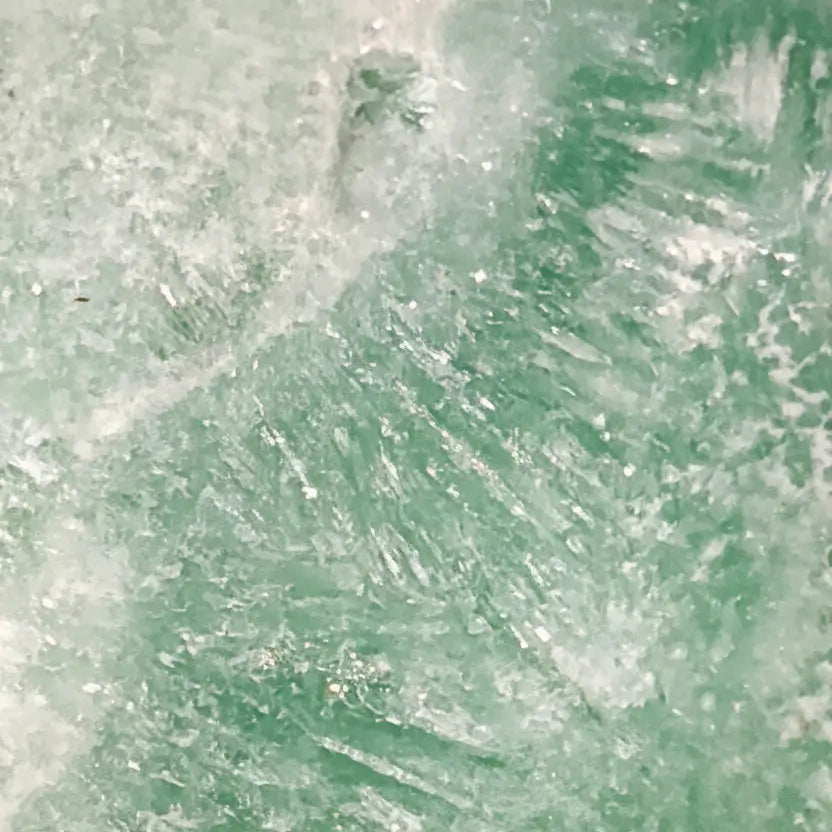close up of a caribbean calcite freeform showing the ice like mineral inclusions  beautiful ocean blues