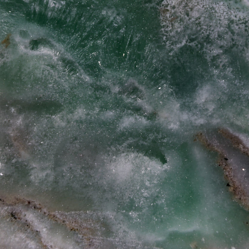A close-up of a Caribbean calcite freeform, showing the soft warm tans and browns from aragonite inclusions, and beautiful ocean green rosettes 