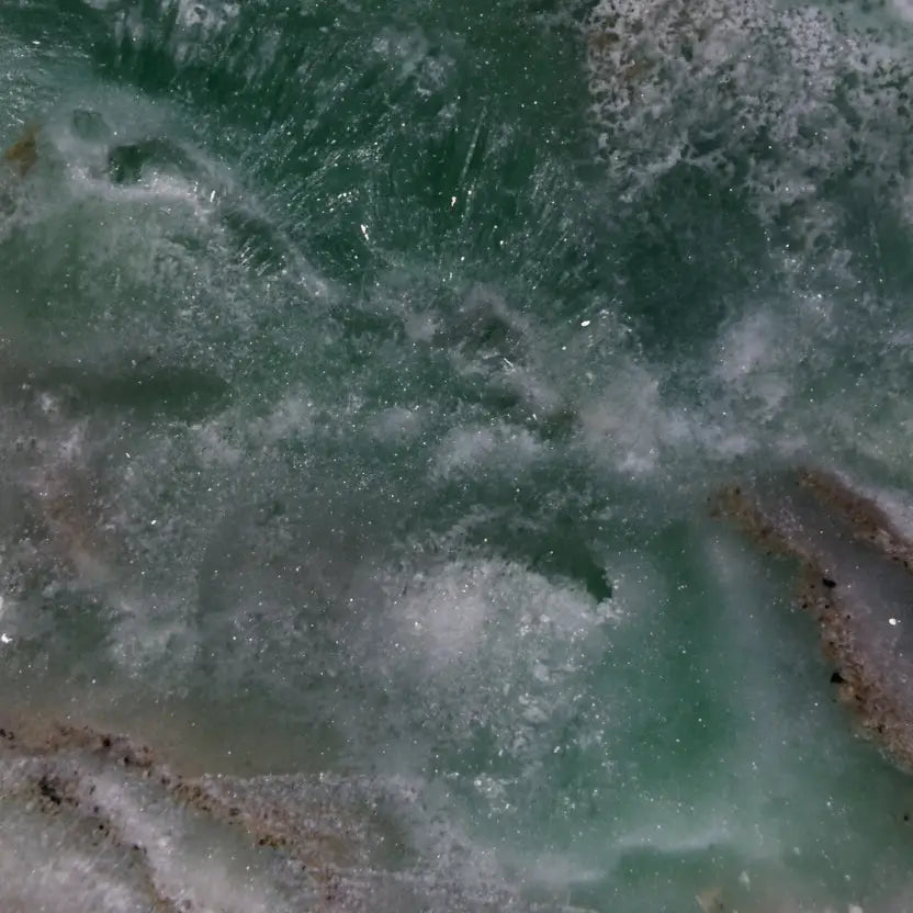 A close-up of a Caribbean calcite freeform, showing the soft warm tans and browns from aragonite inclusions, and beautiful ocean green rosettes 