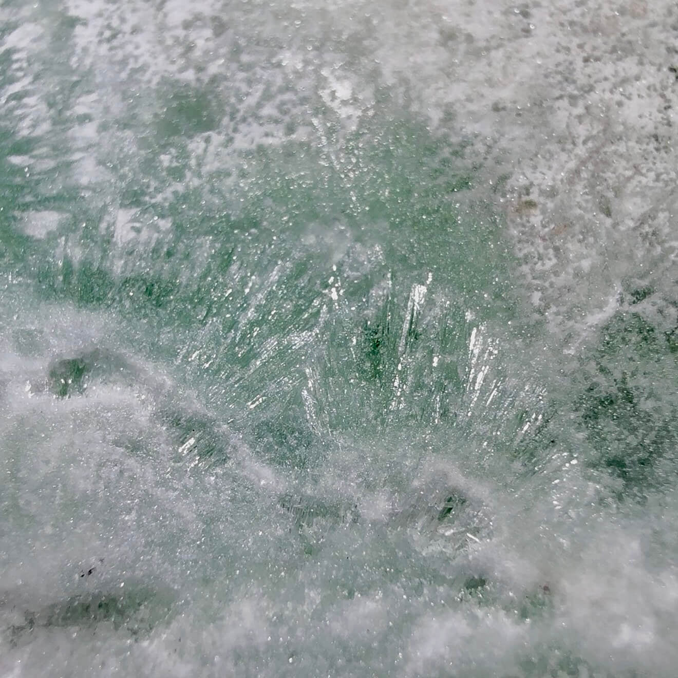 A close-up texture shot of a Caribbean Calcite freeform, resembles ice, frosted glass, or a textured stone.