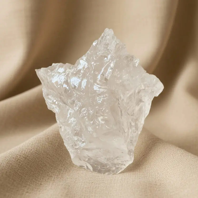 Close up of a clear quartz specimen with a natural cloth background 