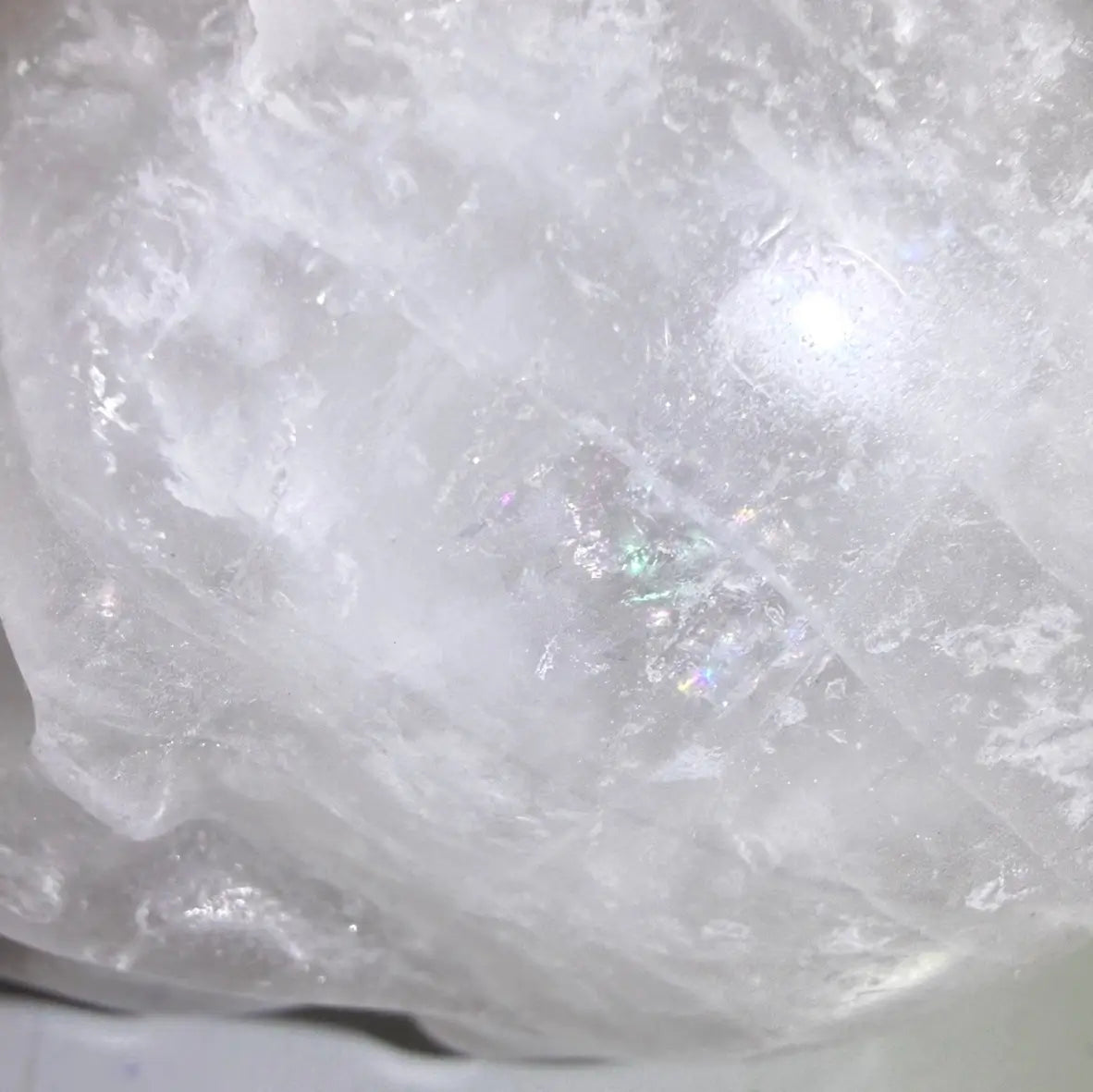 close up clear quartz hand carved skull with rainbows 