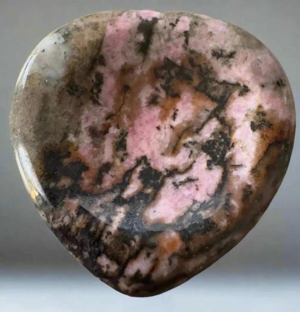 Heart-shaped rhodonite gemstone with pink and black patterns.