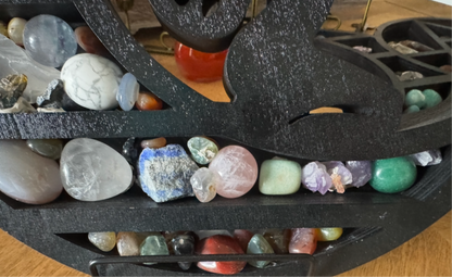 Black tiered shelf filled with tumbled stones.