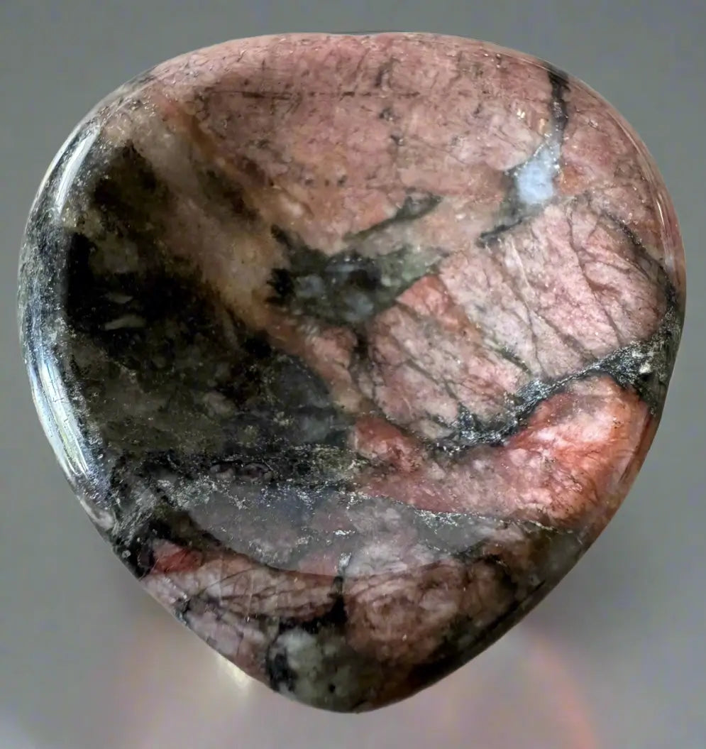 Heart-shaped, polished, pink and black stone.