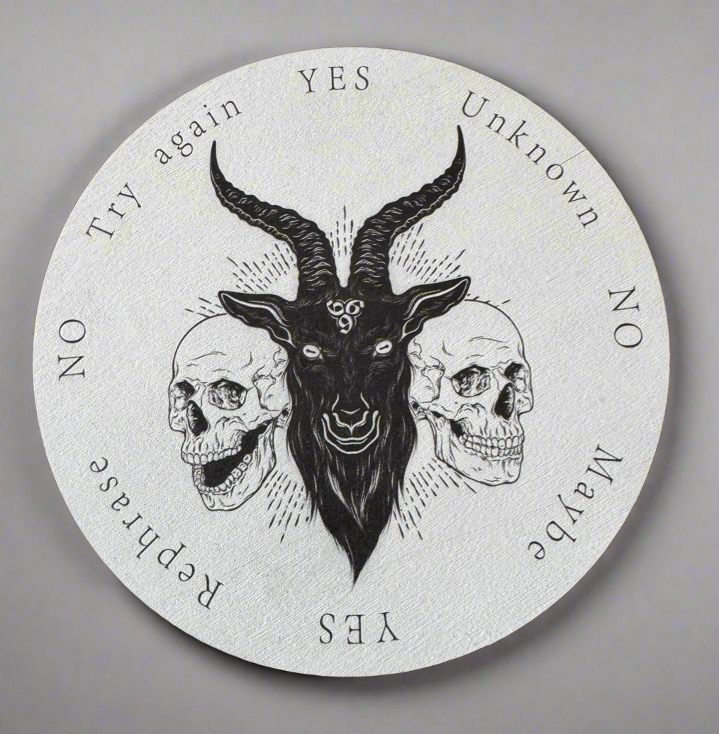 Round ouija board with a black goat head flanked by two skulls, printed with "Yes," "No," "Unknown," "Maybe," "Try again," and "Rephrase" answers.