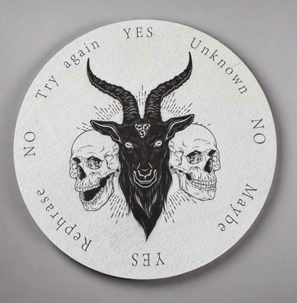Round ouija board with a black goat head flanked by two skulls, printed with "Yes," "No," "Unknown," "Maybe," "Try again," and "Rephrase" answers.