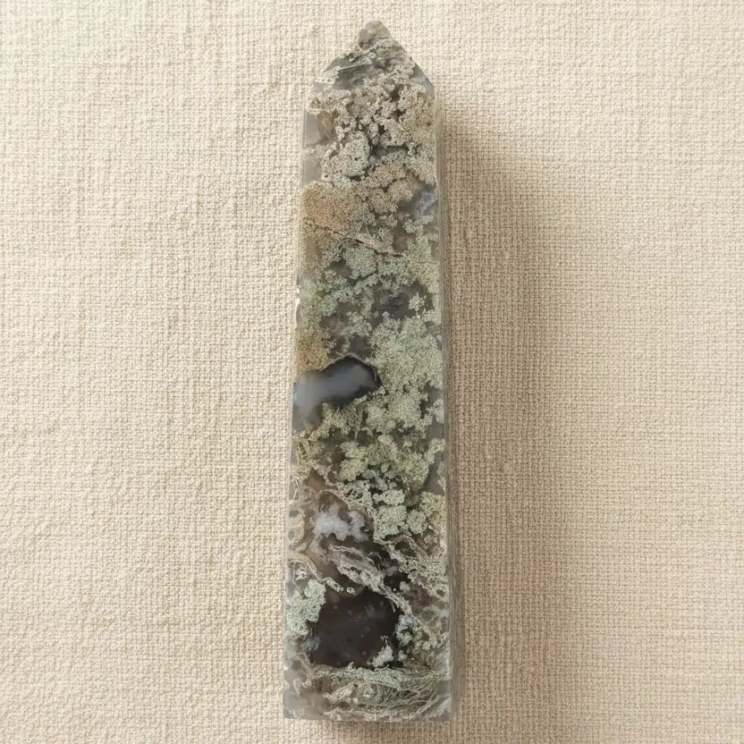 A carved pointed flower agate tower showing possible manganese inclusions, light green mossy and dark green colors