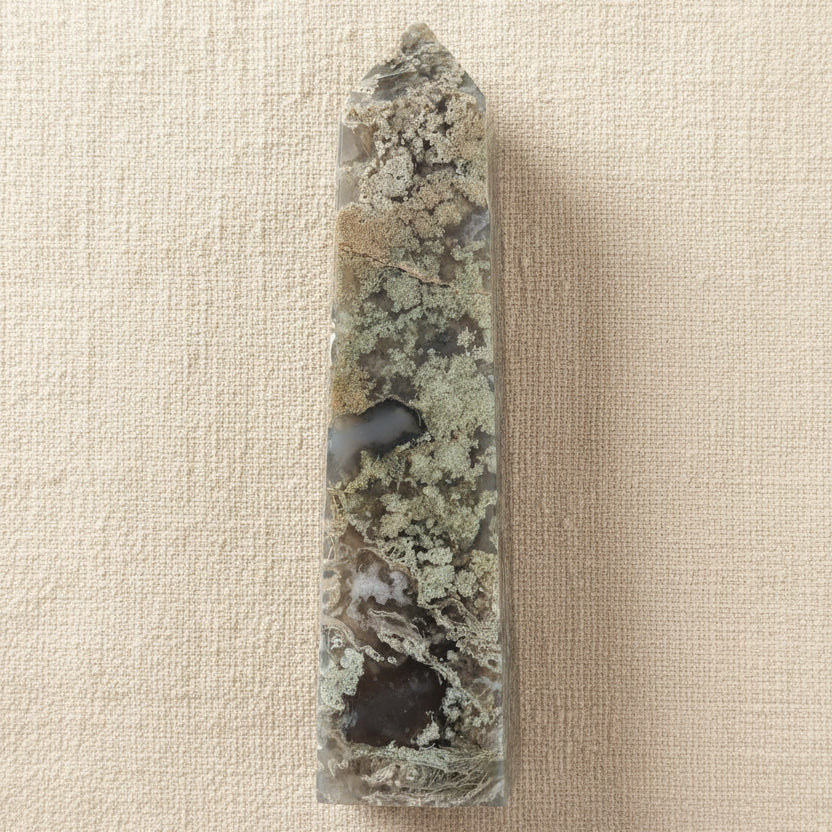 A carved pointed flower agate tower showing possible manganese inclusions, light green mossy and dark green colors