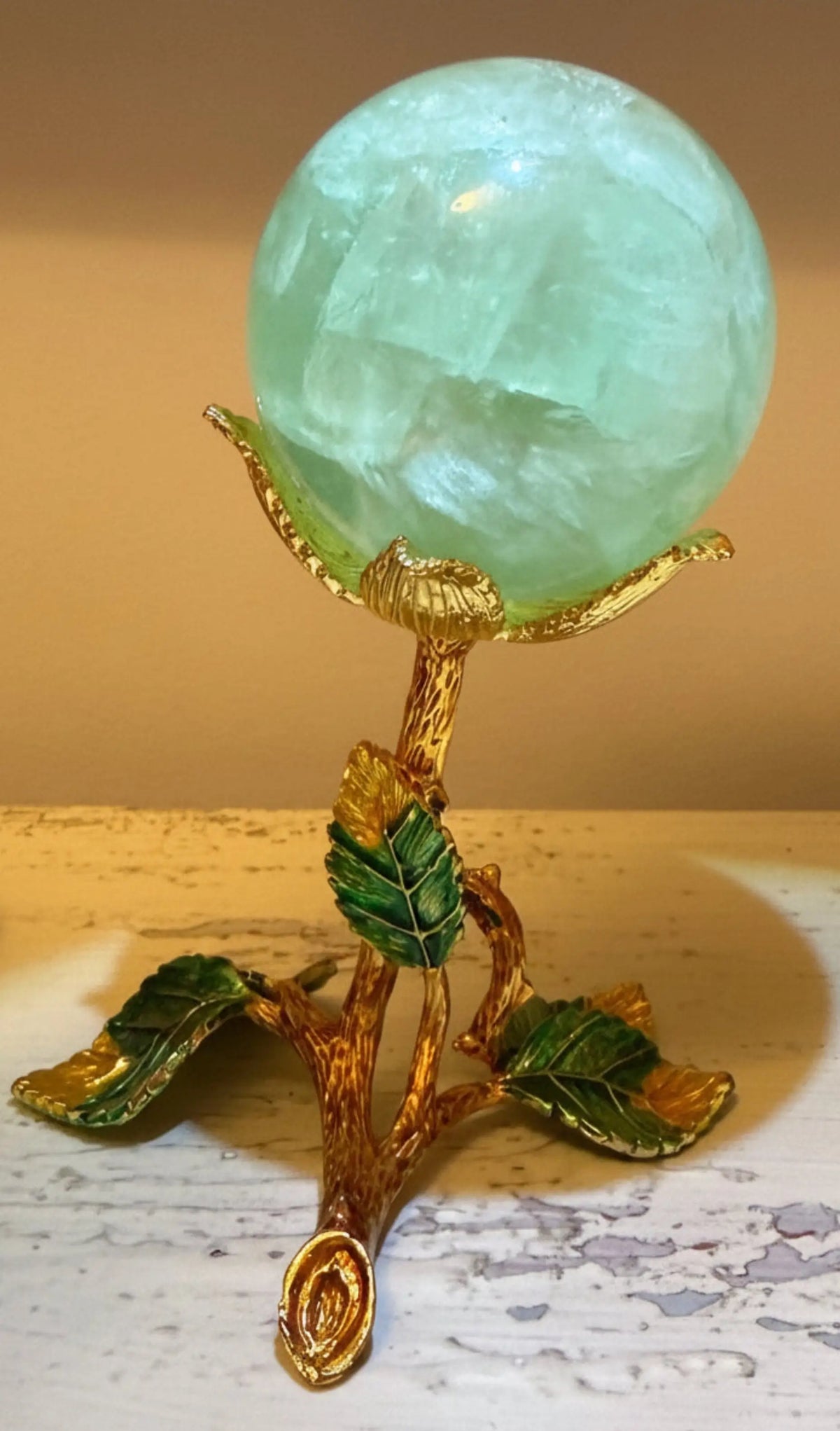 Green and gold floral metal stand for displaying a crystal sphere