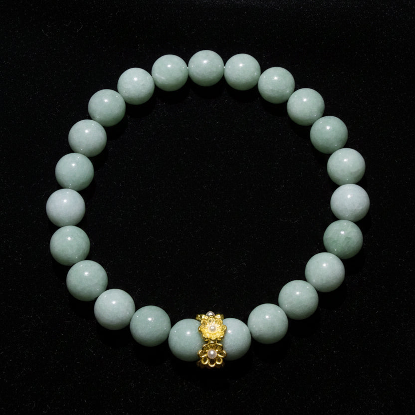 An Aventurine beaded bracelet made of aventurine crystal beads with a central gold-toned decorative charm, photographed on a plain light surface.