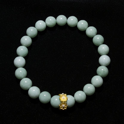 An Aventurine beaded bracelet made of aventurine crystal beads with a central gold-toned decorative charm, photographed on a plain light surface.