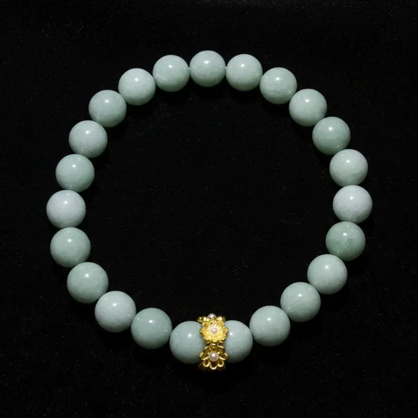 An Aventurine beaded bracelet made of aventurine crystal beads with a central gold-toned decorative charm, photographed on a plain light surface.