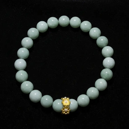 An Aventurine beaded bracelet made of aventurine crystal beads with a central gold-toned decorative charm, photographed on a plain light surface.
