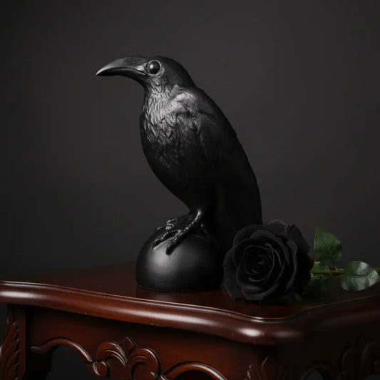 Black crow figurine on a wooden surface with a neutral background