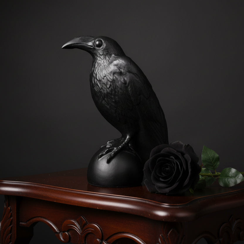 Black crow figurine on a wooden surface with a neutral background